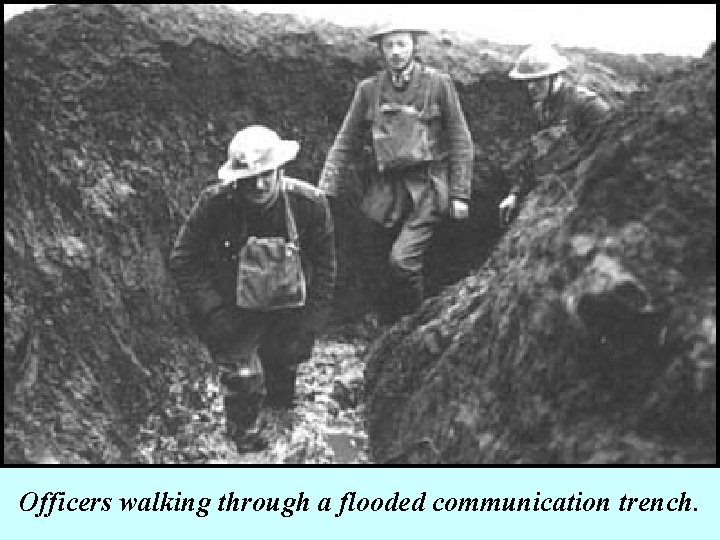 Officers walking through a flooded communication trench. 