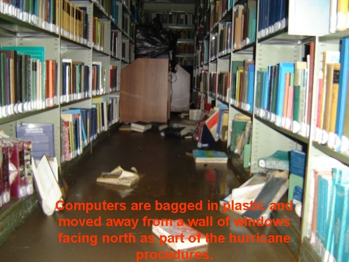 Computers are bagged in plastic and moved away from a wall of windows facing