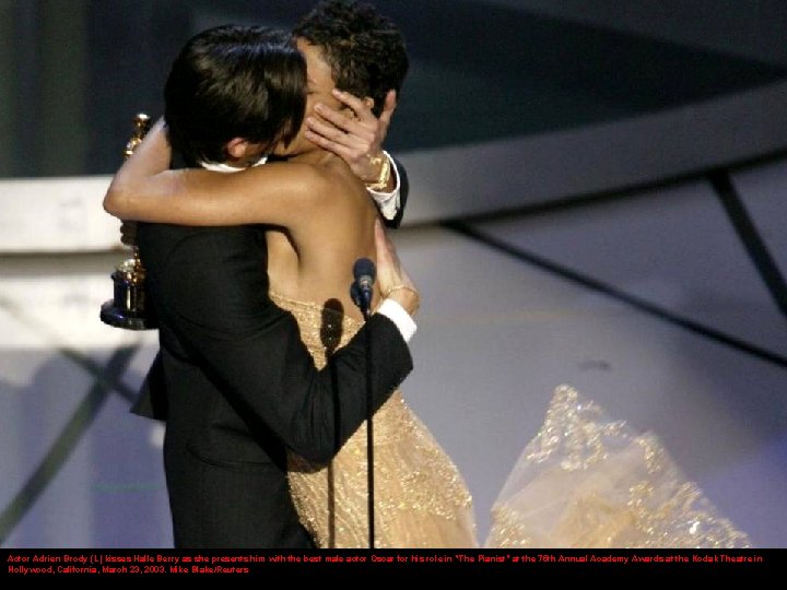 Actor Adrien Brody (L) kisses Halle Berry as she presents him with the best