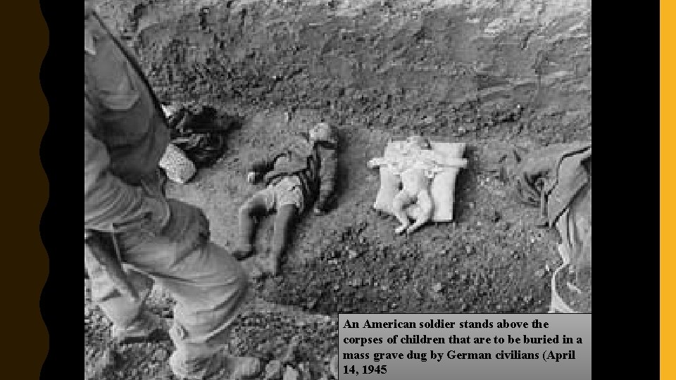 An American soldier stands above the corpses of children that are to be buried