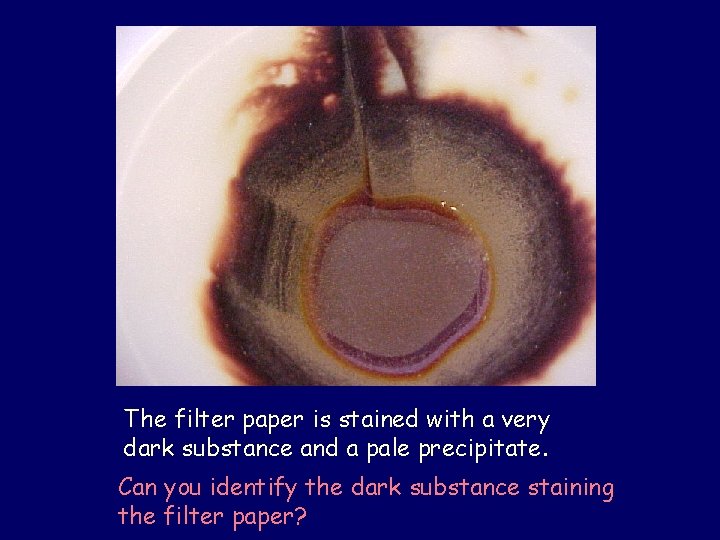 The filter paper is stained with a very dark substance and a pale precipitate.