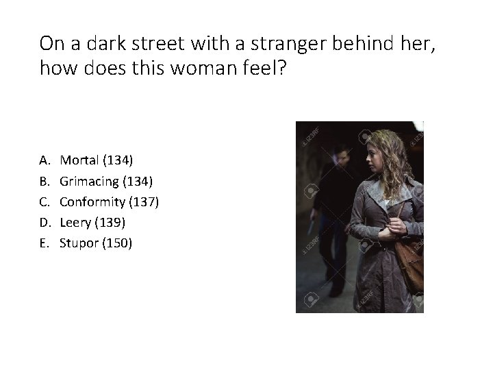On a dark street with a stranger behind her, how does this woman feel?