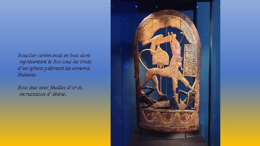 Bouclier cérémonial en bois doré représentant le Roi sous les traits d’un sphinx piétinant