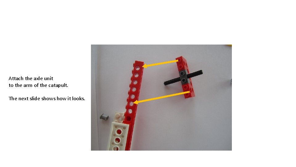 Attach the axle unit to the arm of the catapult. The next slide shows