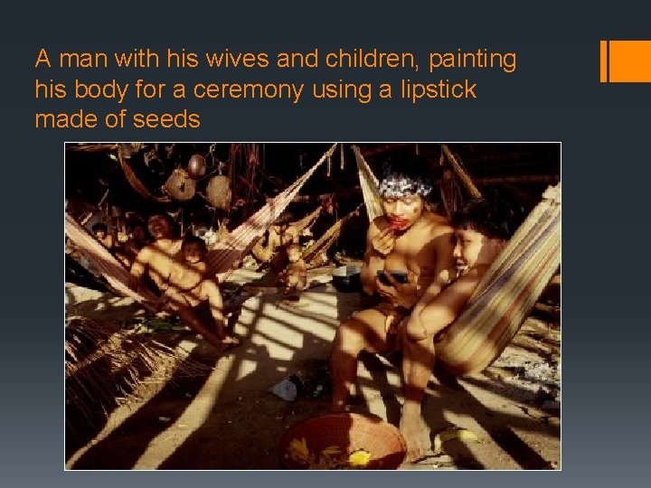 A man with his wives and children, painting his body for a ceremony using