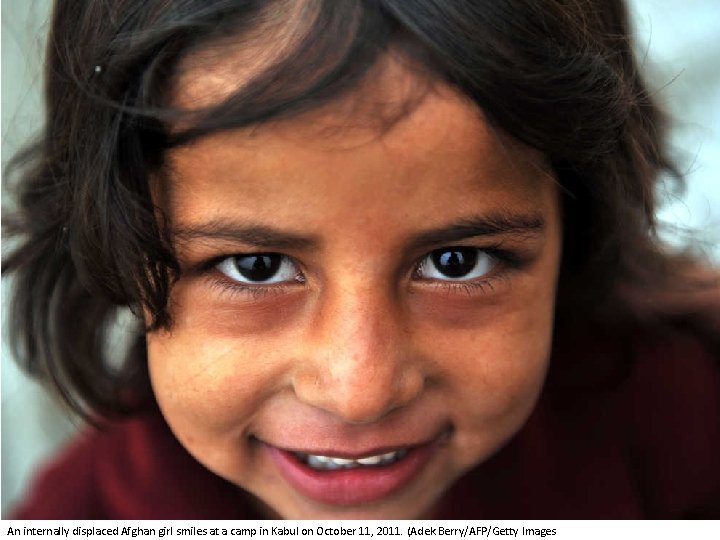 An internally displaced Afghan girl smiles at a camp in Kabul on October 11,