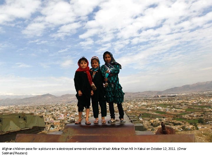 Afghan children pose for a picture on a destroyed armored vehicle on Wazir Akbar