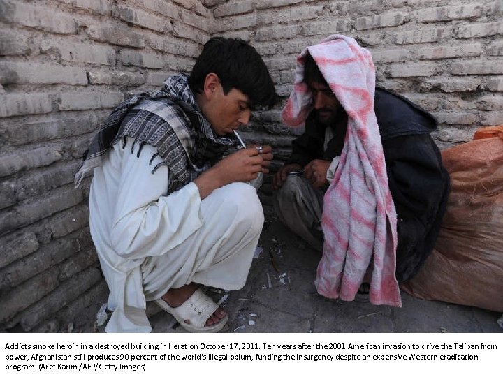 Addicts smoke heroin in a destroyed building in Herat on October 17, 2011. Ten