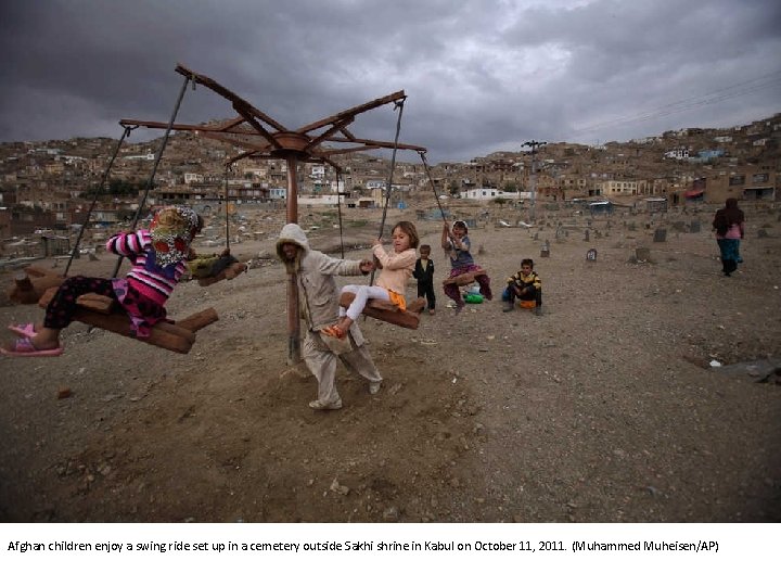 Afghan children enjoy a swing ride set up in a cemetery outside Sakhi shrine