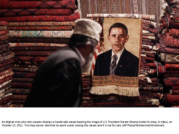 An Afghan man who sells carpets displays a handmade carpet bearing the image of