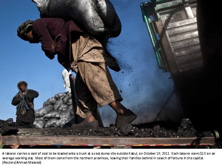 A laborer carries a sack of coal to be loaded onto a truck at