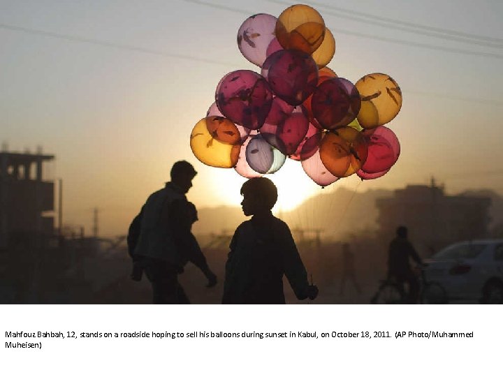 Mahfouz Bahbah, 12, stands on a roadside hoping to sell his balloons during sunset