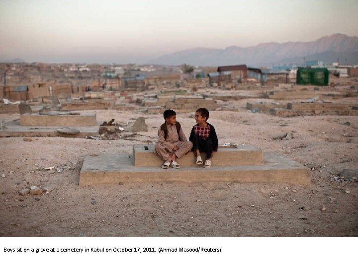 Boys sit on a grave at a cemetery in Kabul on October 17, 2011.