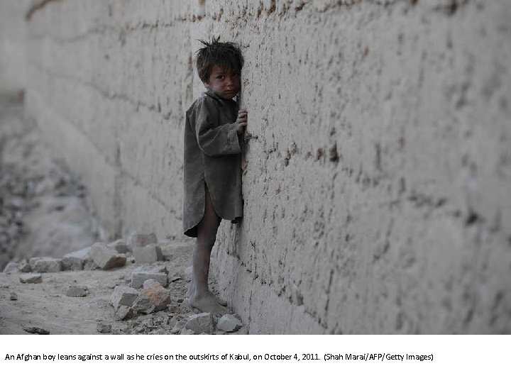 An Afghan boy leans against a wall as he cries on the outskirts of