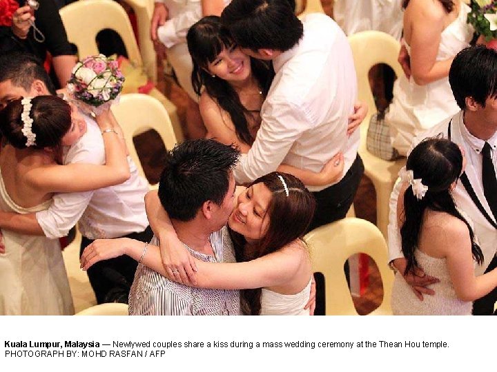 Kuala Lumpur, Malaysia — Newlywed couples share a kiss during a mass wedding ceremony