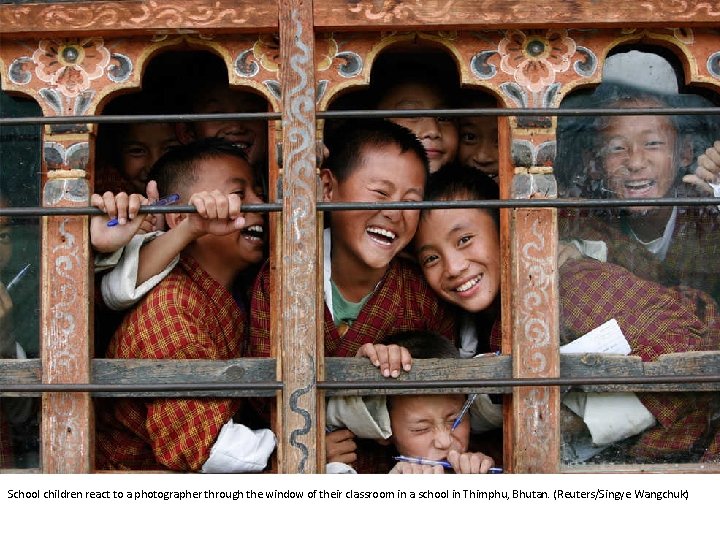 School children react to a photographer through the window of their classroom in a