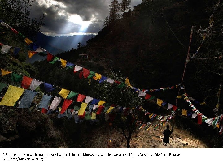 A Bhutanese man walks past prayer flags at Taktsang Monastery, also known as the