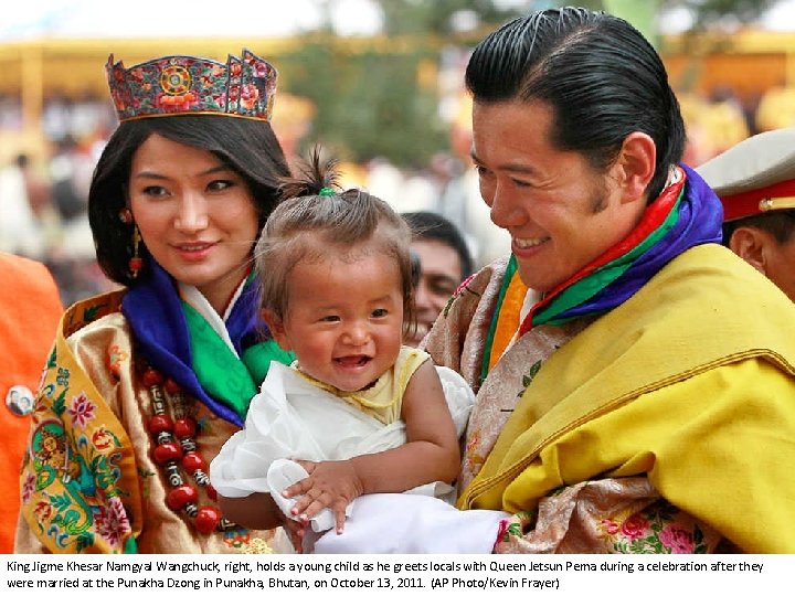 King Jigme Khesar Namgyal Wangchuck, right, holds a young child as he greets locals