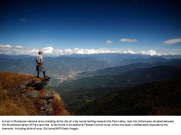 A man in Bhutanese national dress standing at the site of a sky burial