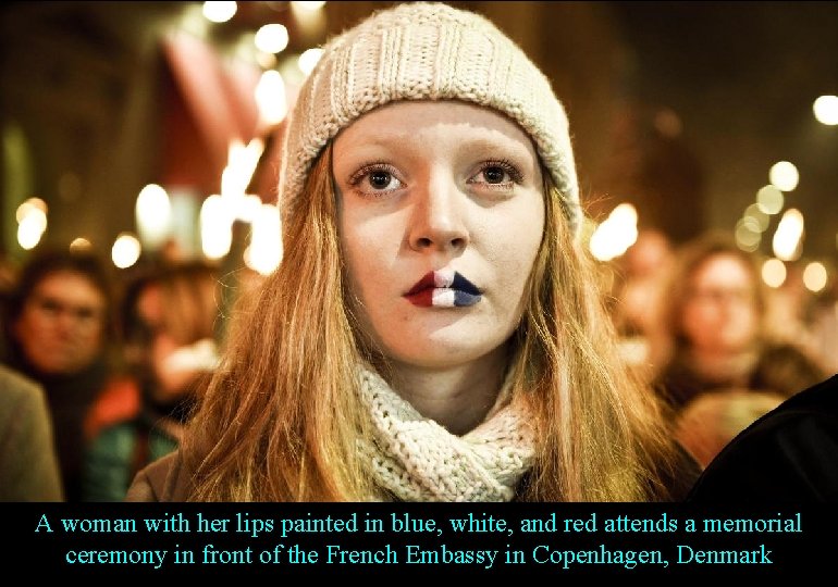 A woman with her lips painted in blue, white, and red attends a memorial