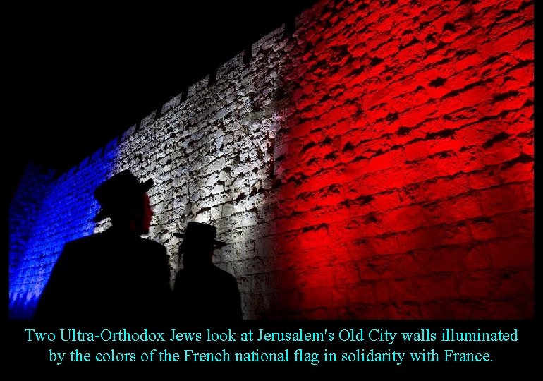 Two Ultra-Orthodox Jews look at Jerusalem's Old City walls illuminated by the colors of