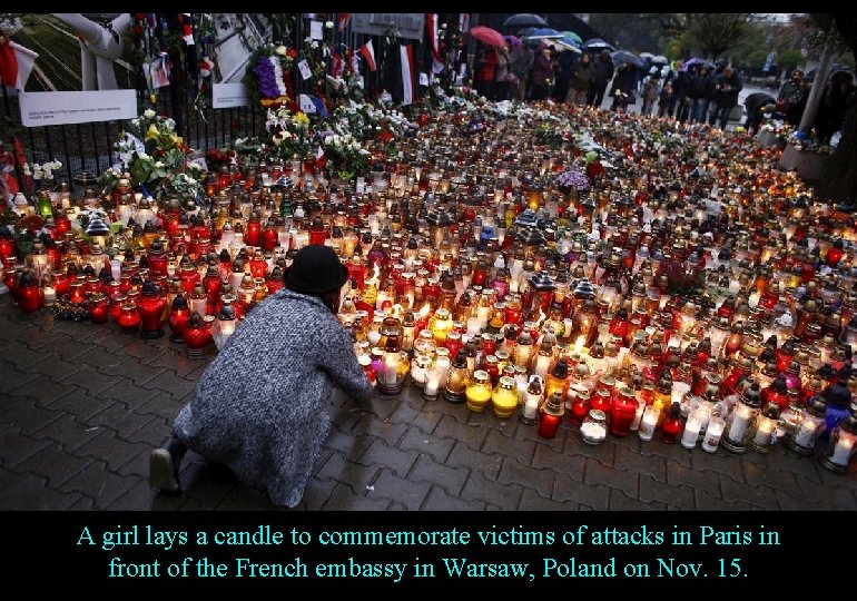 A girl lays a candle to commemorate victims of attacks in Paris in front