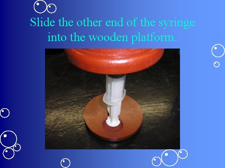 Slide the other end of the syringe into the wooden platform. 