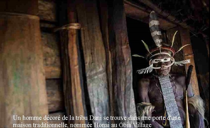 Un homme décoré de la tribu Dani se trouve dans une porte d'une maison
