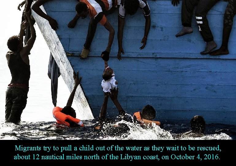 Migrants try to pull a child out of the water as they wait to