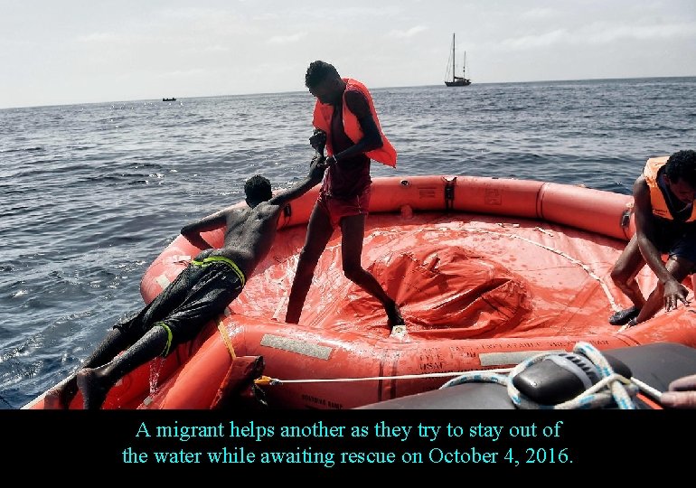 A migrant helps another as they try to stay out of the water while