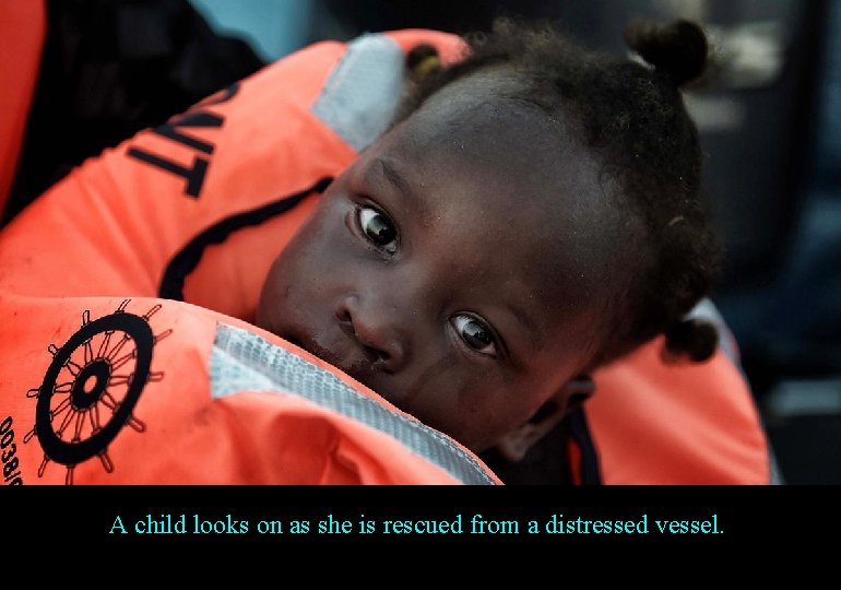 A child looks on as she is rescued from a distressed vessel. 