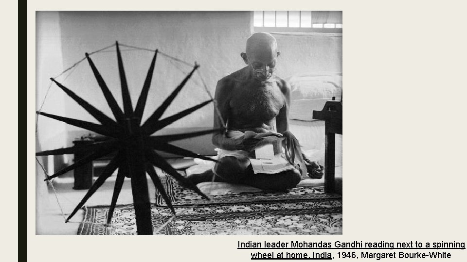 Indian leader Mohandas Gandhi reading next to a spinning wheel at home. India, 1946,