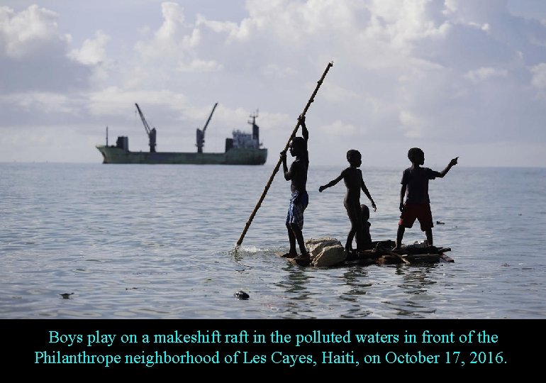 Boys play on a makeshift raft in the polluted waters in front of the