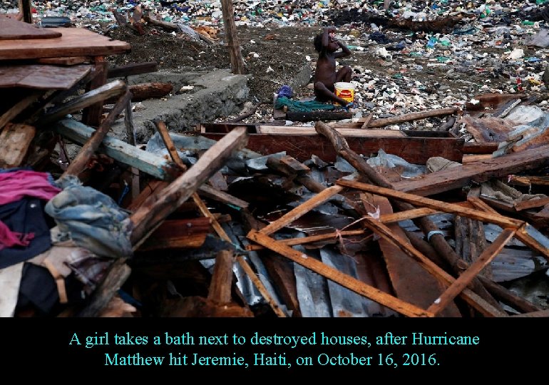 A girl takes a bath next to destroyed houses, after Hurricane Matthew hit Jeremie,