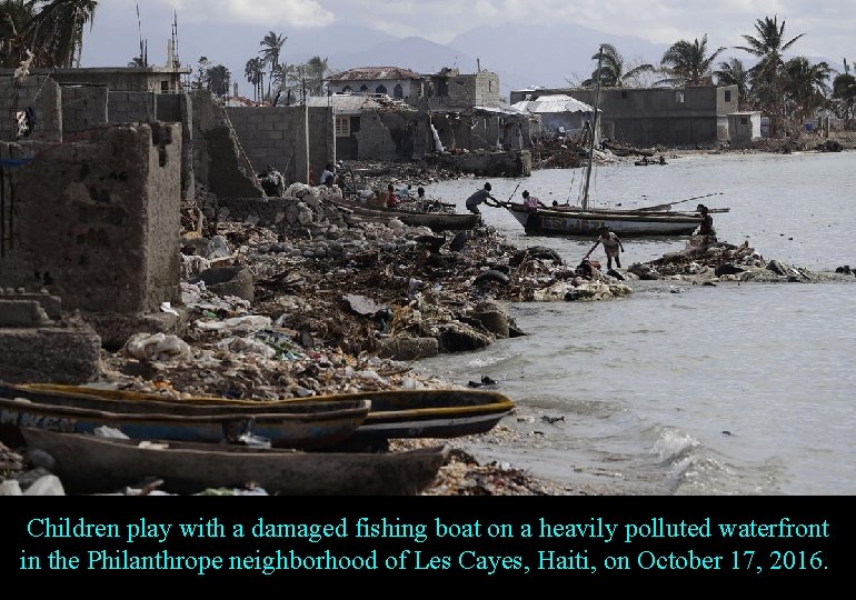 Children play with a damaged fishing boat on a heavily polluted waterfront in the