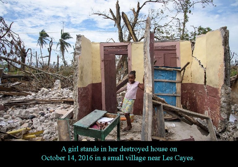 A girl stands in her destroyed house on October 14, 2016 in a small