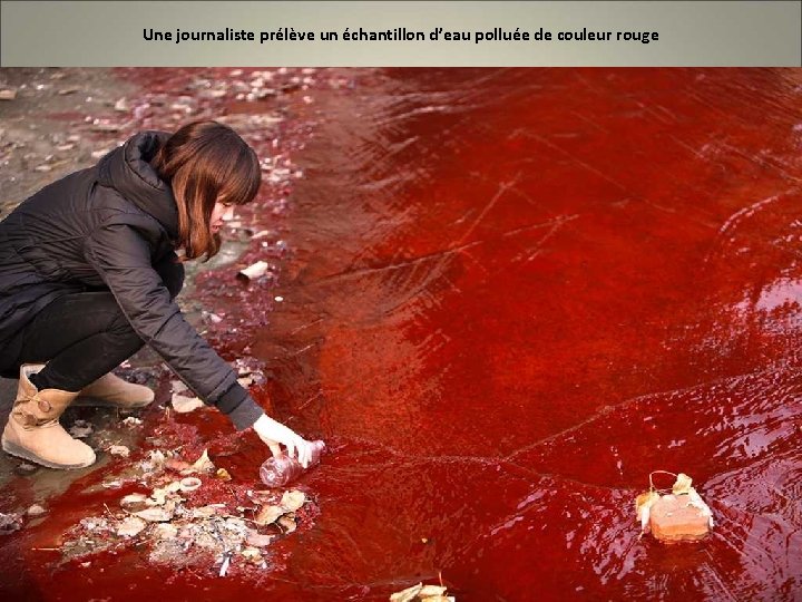 Une journaliste prélève un échantillon d’eau polluée de couleur rouge 