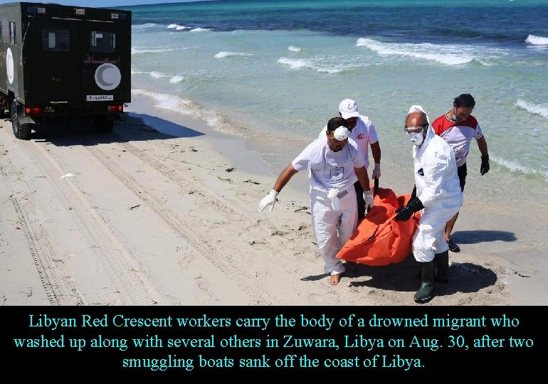 Libyan Red Crescent workers carry the body of a drowned migrant who washed up