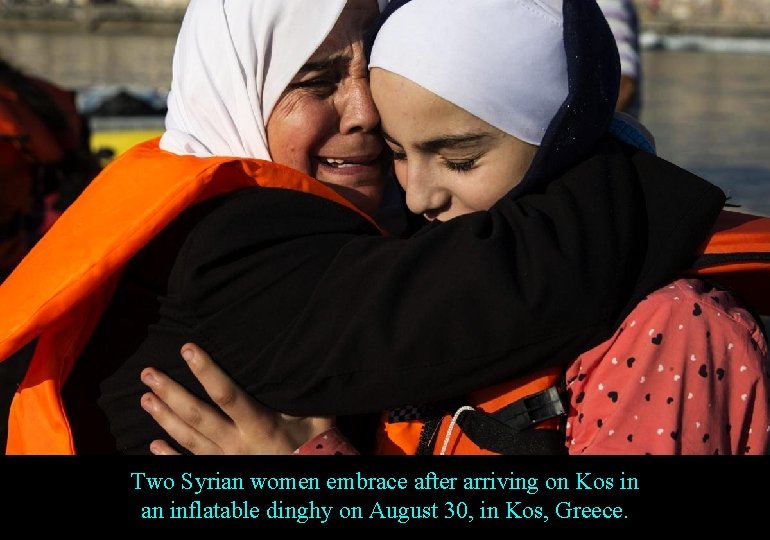 Two Syrian women embrace after arriving on Kos in an inflatable dinghy on August