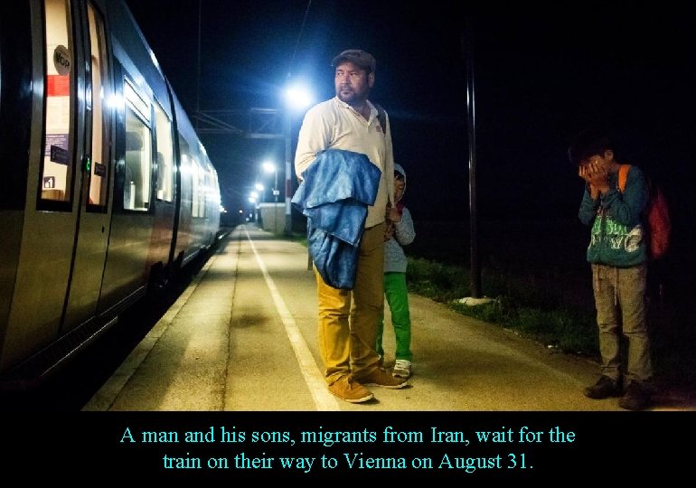 A man and his sons, migrants from Iran, wait for the train on their