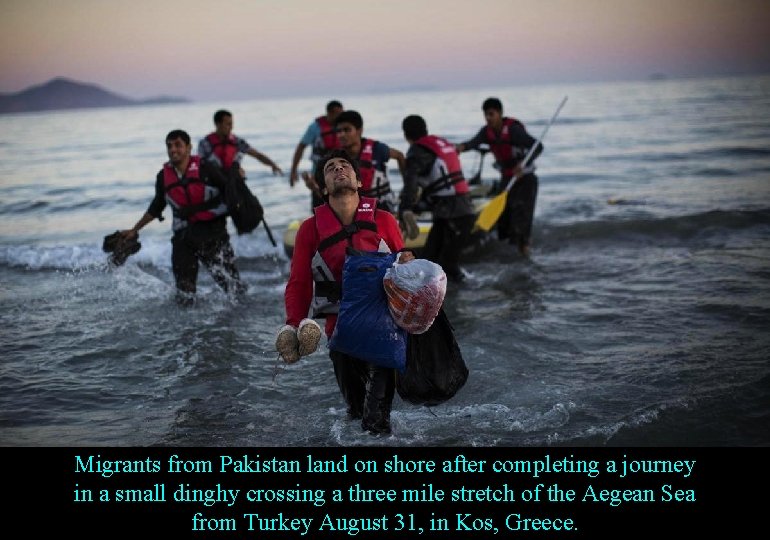 Migrants from Pakistan land on shore after completing a journey in a small dinghy