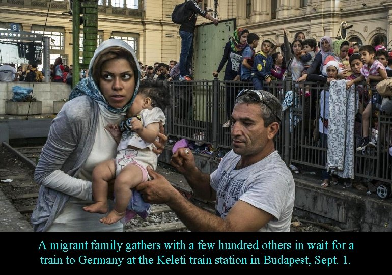 A migrant family gathers with a few hundred others in wait for a train