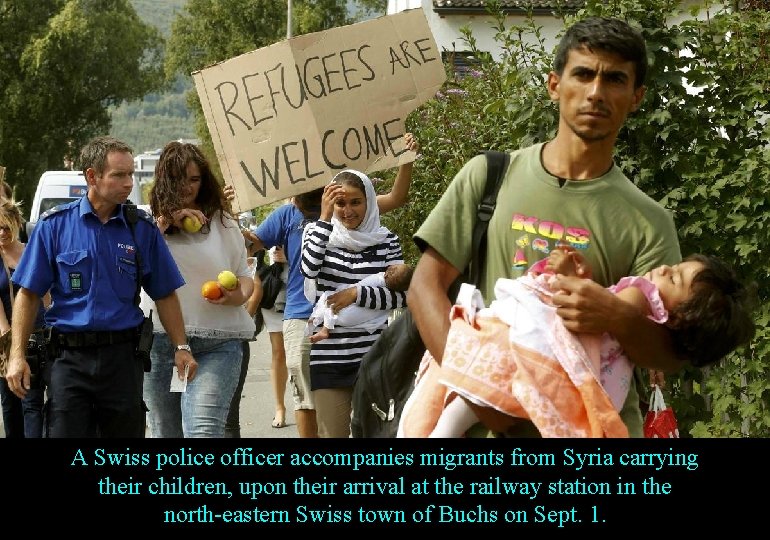 A Swiss police officer accompanies migrants from Syria carrying their children, upon their arrival