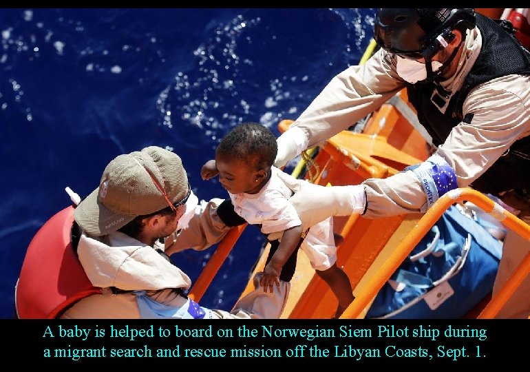 A baby is helped to board on the Norwegian Siem Pilot ship during a