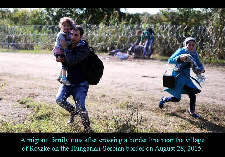 A migrant family runs after crossing a border line near the village of Roszke