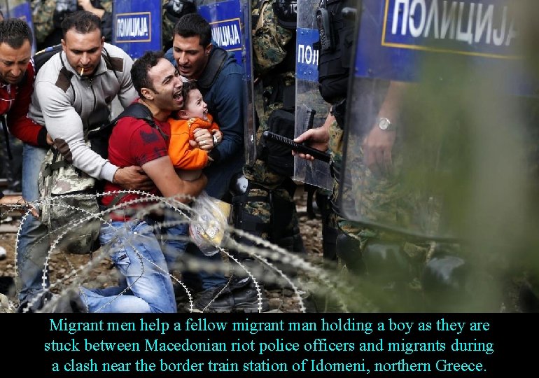 Migrant men help a fellow migrant man holding a boy as they are stuck