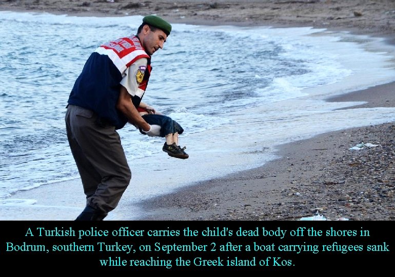 A Turkish police officer carries the child's dead body off the shores in Bodrum,