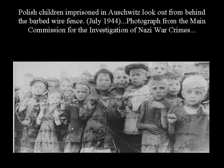 Polish children imprisoned in Auschwitz look out from behind the barbed wire fence. (July
