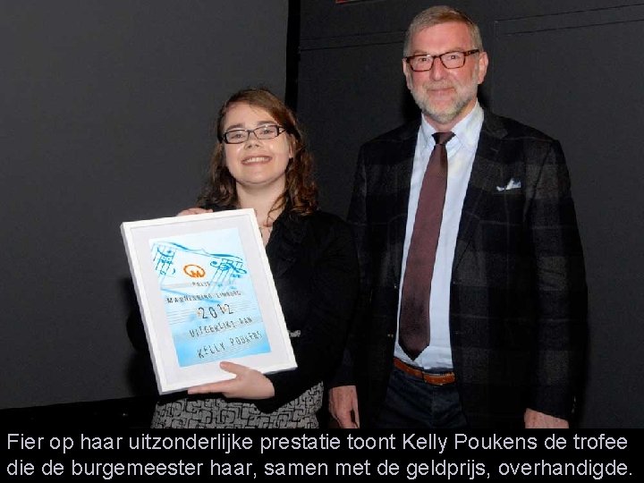 Fier op haar uitzonderlijke prestatie toont Kelly Poukens de trofee die de burgemeester haar,