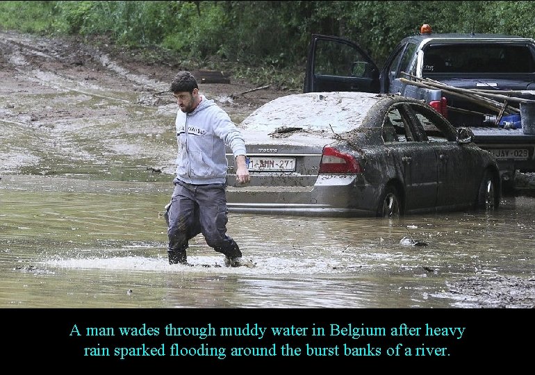 A man wades through muddy water in Belgium after heavy rain sparked flooding around